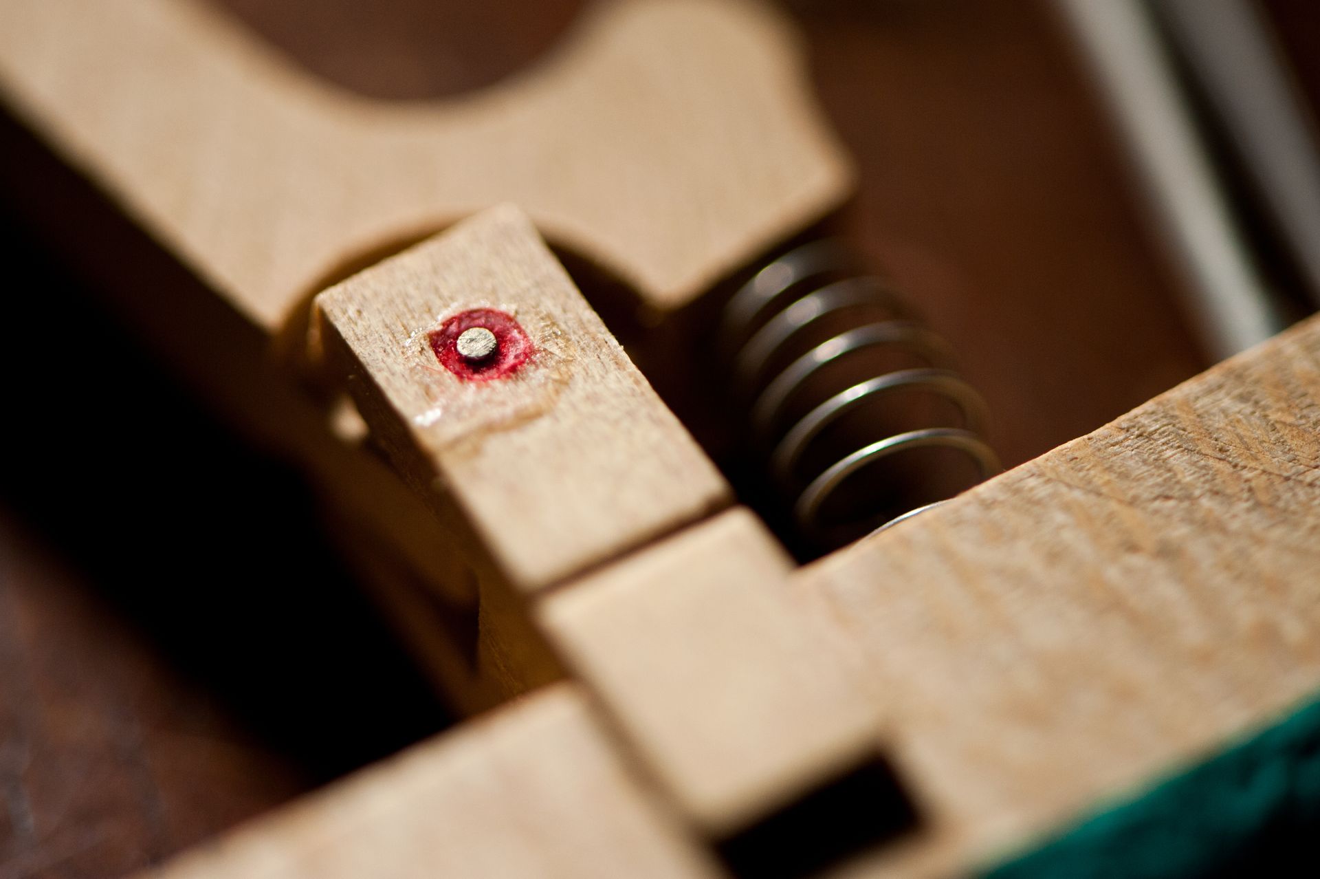 Close-up of piano mechanism. Wooden parts, spring, and red dot.