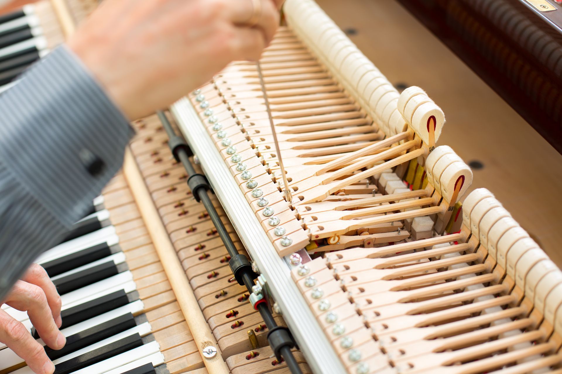A man is working on the inside of a piano.