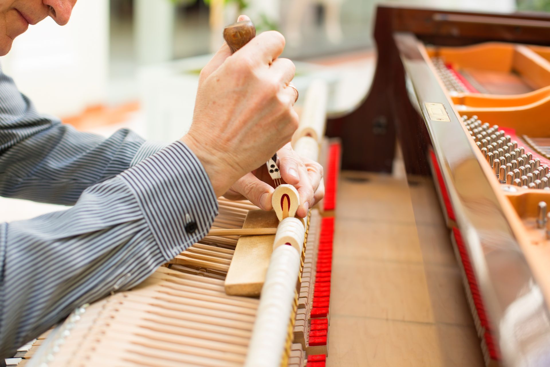 A man is working on a piano with a hammer.