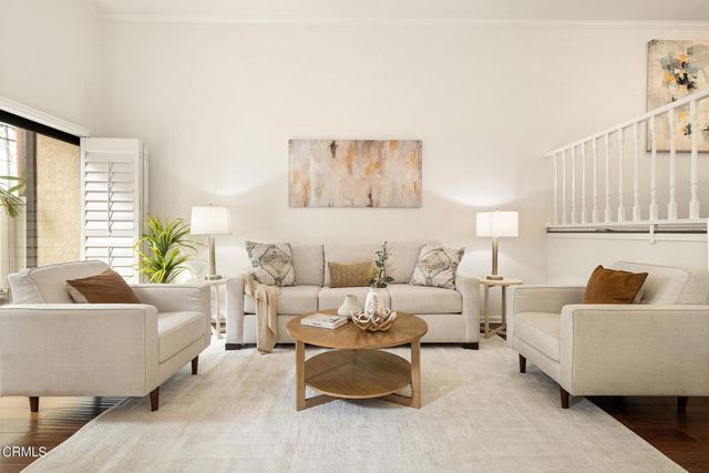 A living room with a couch , two chairs , a coffee table and a painting on the wall.