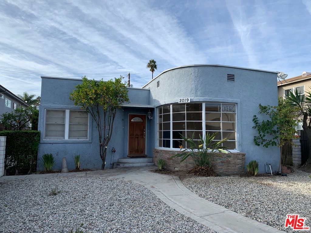 A blue house with a lot of windows and a gravel driveway.