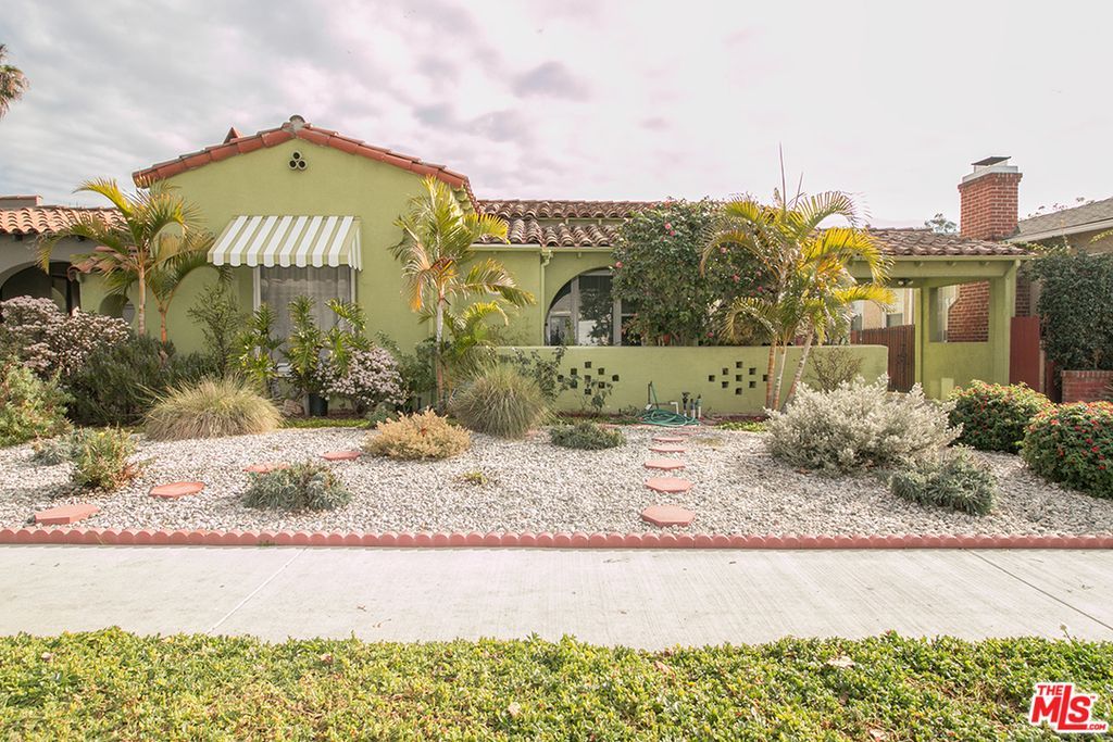A green house with a white awning on the front of it is for sale.