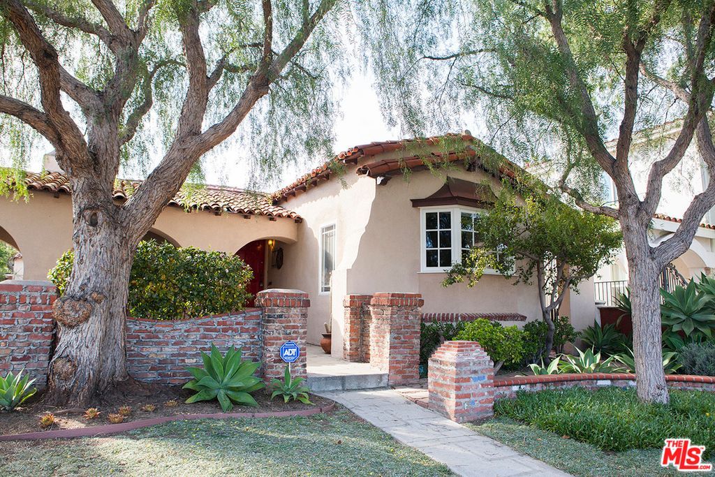 A house with a brick wall and trees in front of it