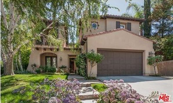 A large house with a brown garage door is for sale