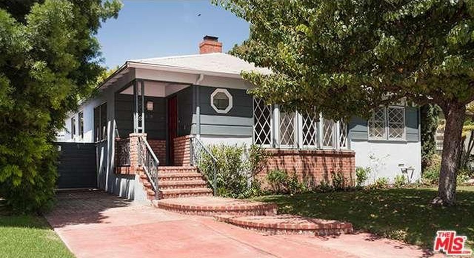 A small house with a porch and stairs is for sale