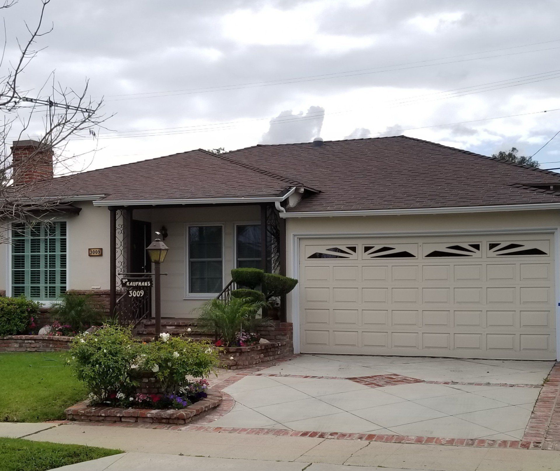 A white house with a brown roof and a white garage door