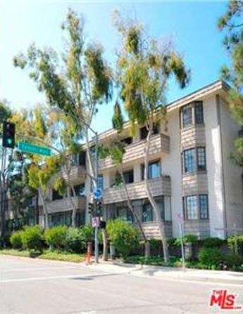 A large apartment building is sitting on the corner of a street.