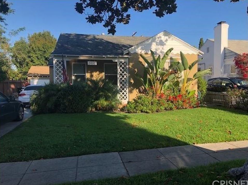 A house with a lot of grass and cars parked in front of it