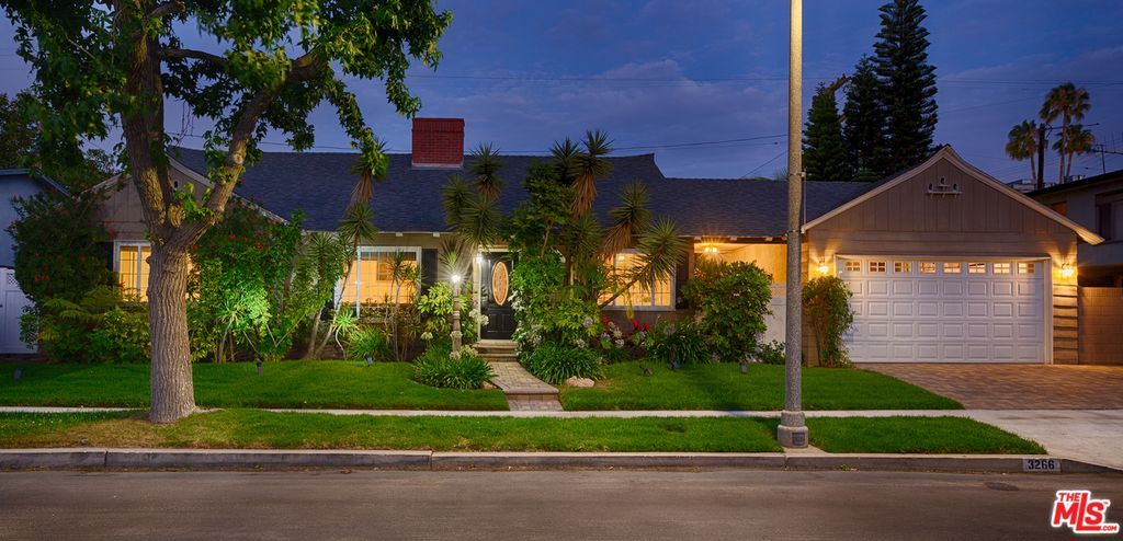 A house is lit up at night with a street light in front of it.