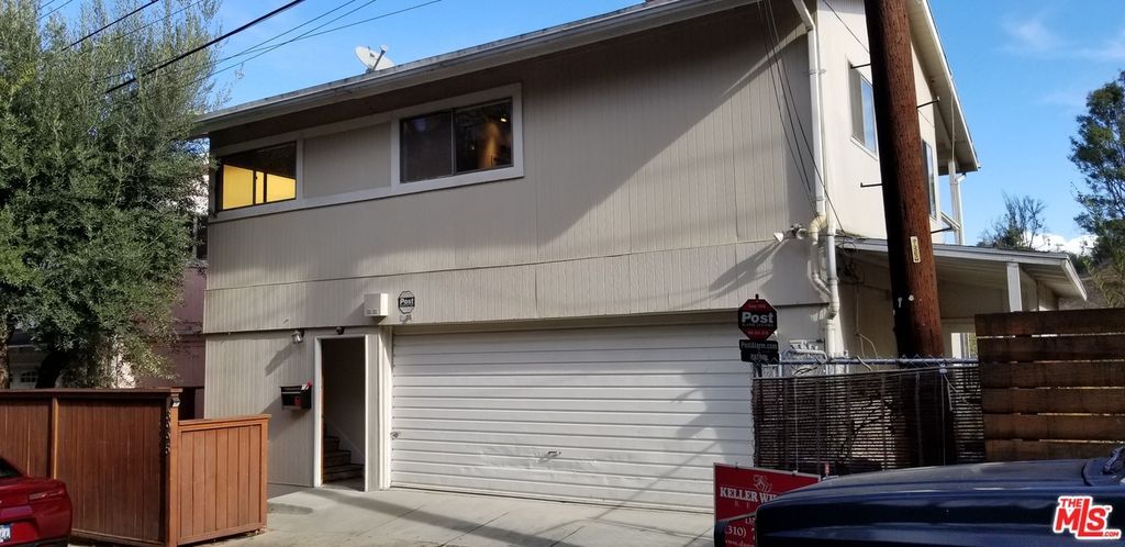A house with a white garage door and a red car parked in front of it.
