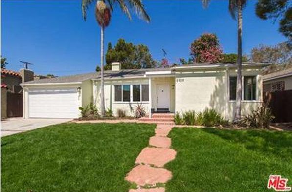 A white house with a lush green lawn and a walkway leading to it.