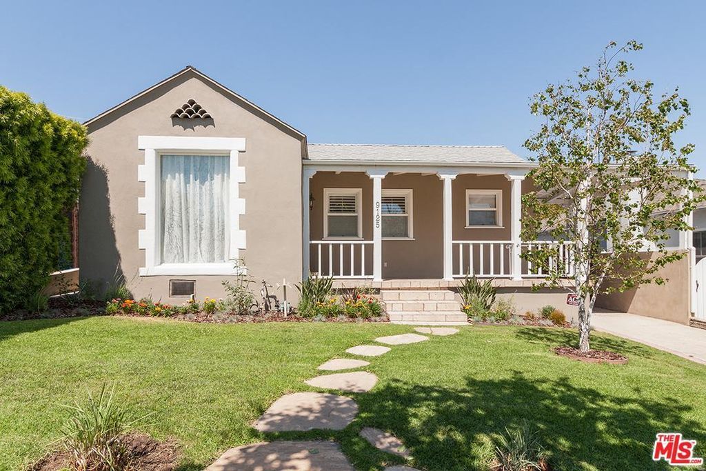 A house with a lush green lawn and a walkway leading to it.