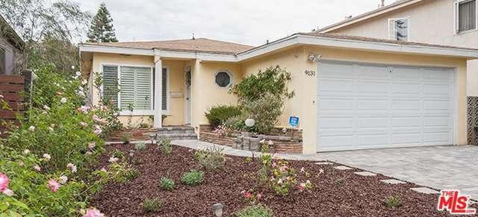 A yellow house with a white garage door is for sale.