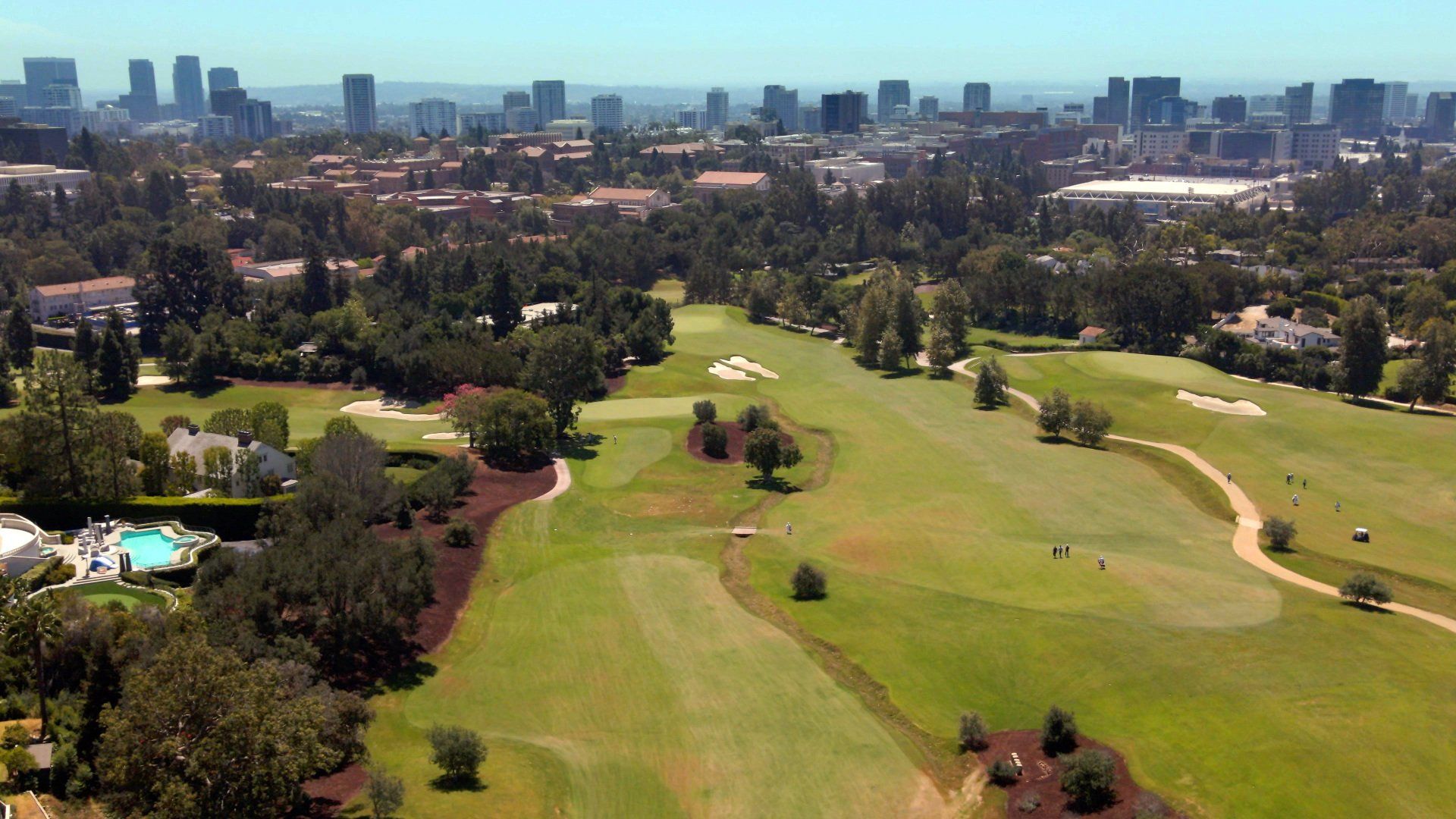 An aerial view of a golf course with a city in the background.