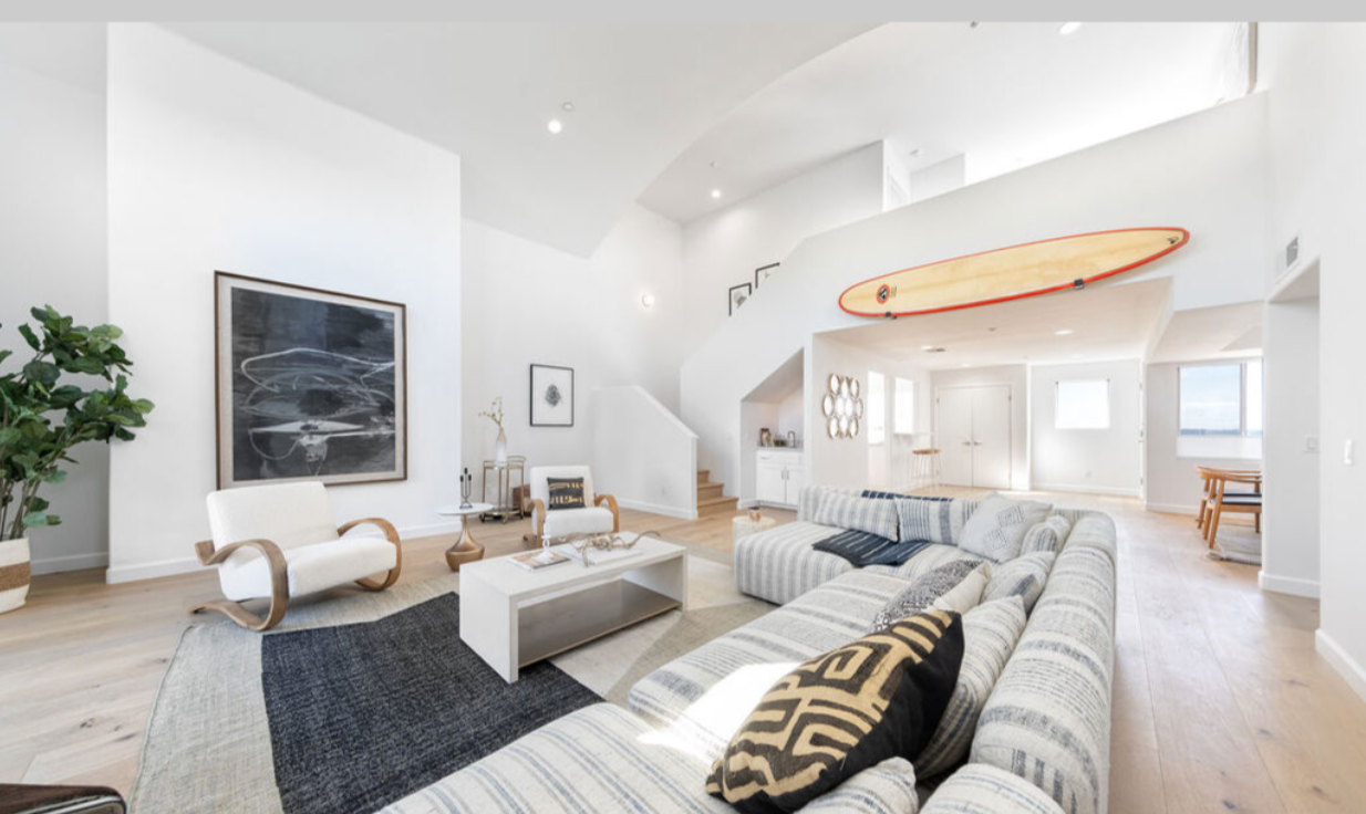 A living room with a couch and a surfboard on the wall
