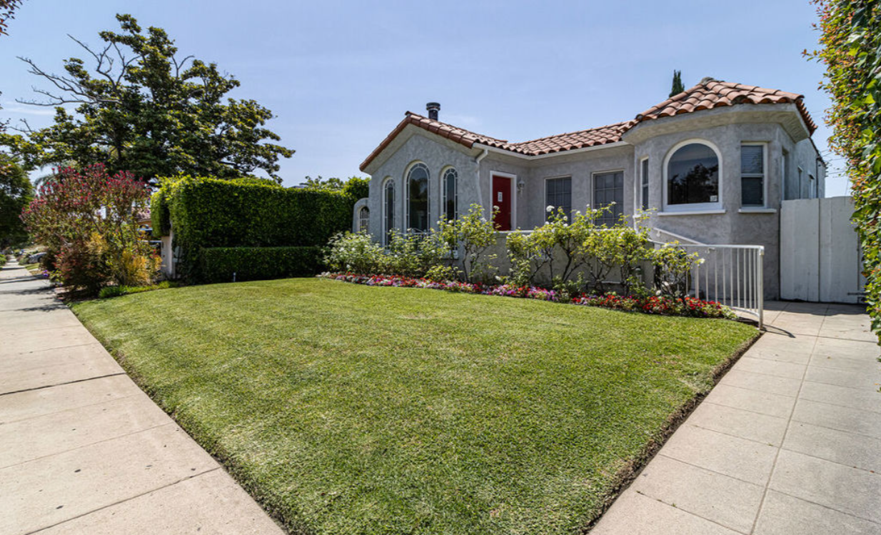 A white house with a red door and a lush green lawn