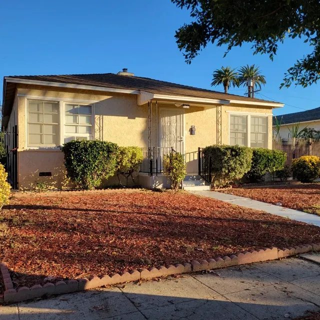 A house with a lot of leaves on the ground in front of it