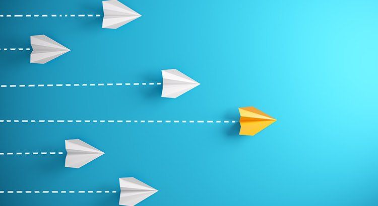 A yellow paper airplane is leading a row of white paper airplanes on a blue background.