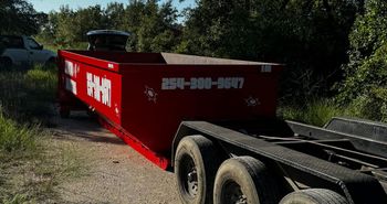 A red dumpster is sitting on top of a trailer.