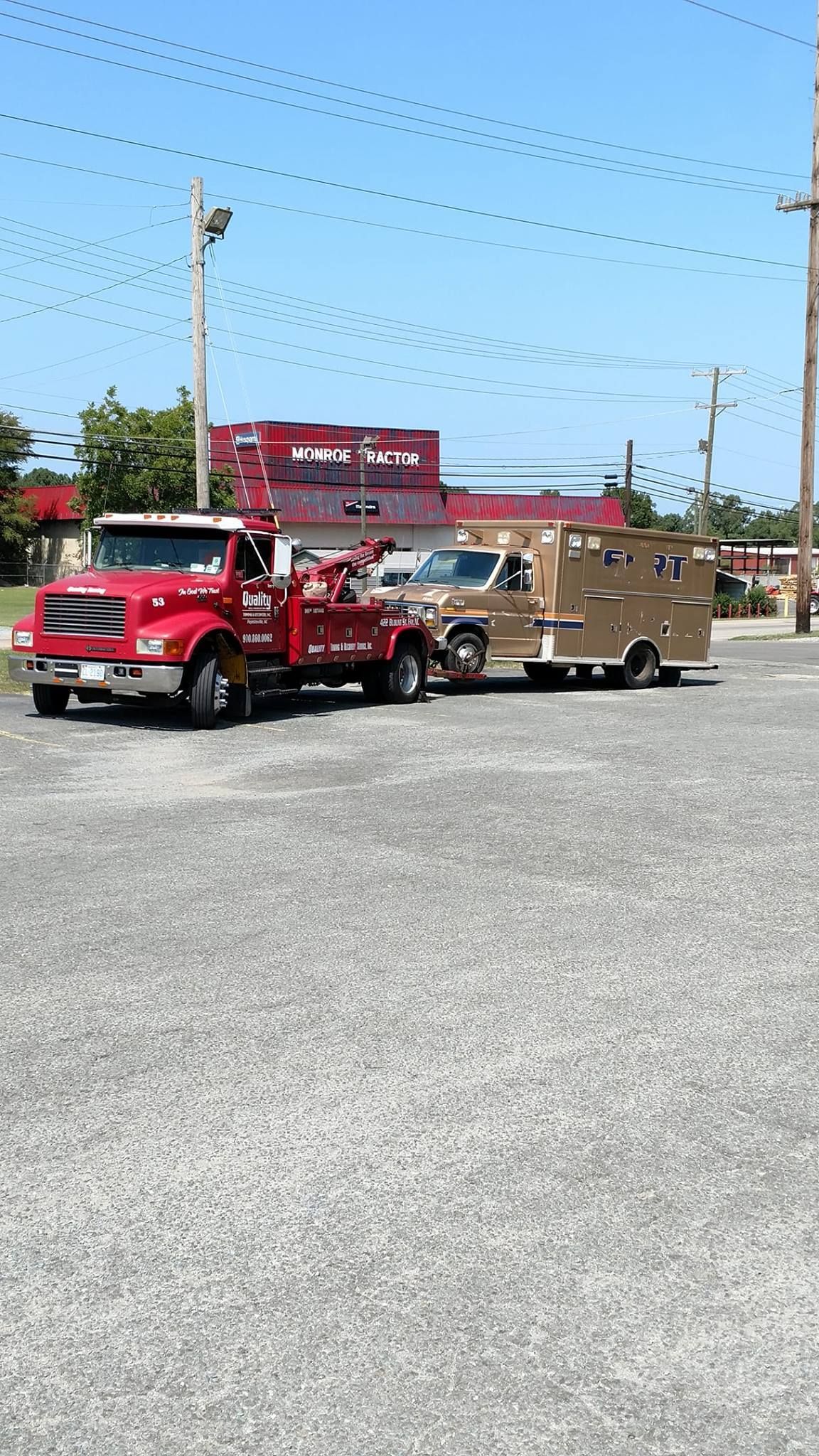 two tow trucks are parked in a gravel lot .