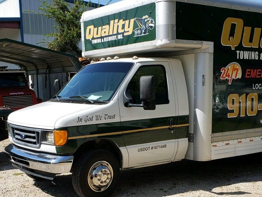 a quality towing truck is parked in a gravel lot