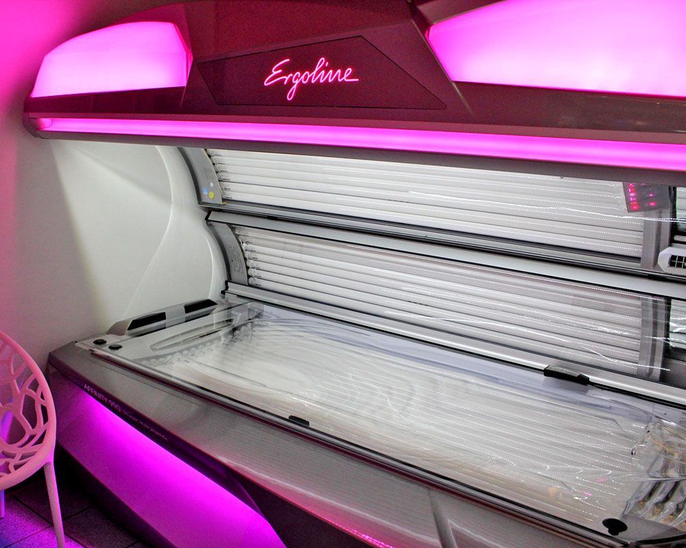 Solarium mit rosa Beleuchtung. Das Ergoline-Logo ist sichtbar. Die Liege ist ausgeklappt und leer.