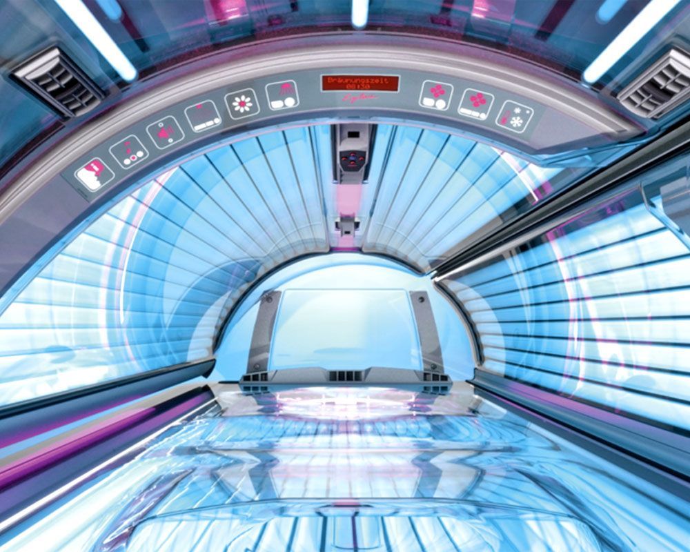 Innenansicht eines Solariums mit hellblauen UV-Lampen und Bedienfeld.