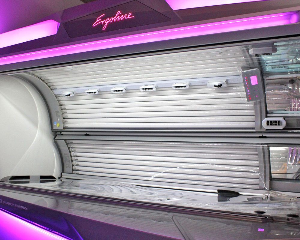 Ergoline-Solarienbank, Innenansicht, mit hellweißen Röhren und violetter Beleuchtung.