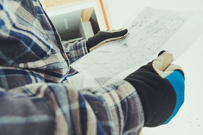 A man wearing gloves is holding a piece of paper in his hands.