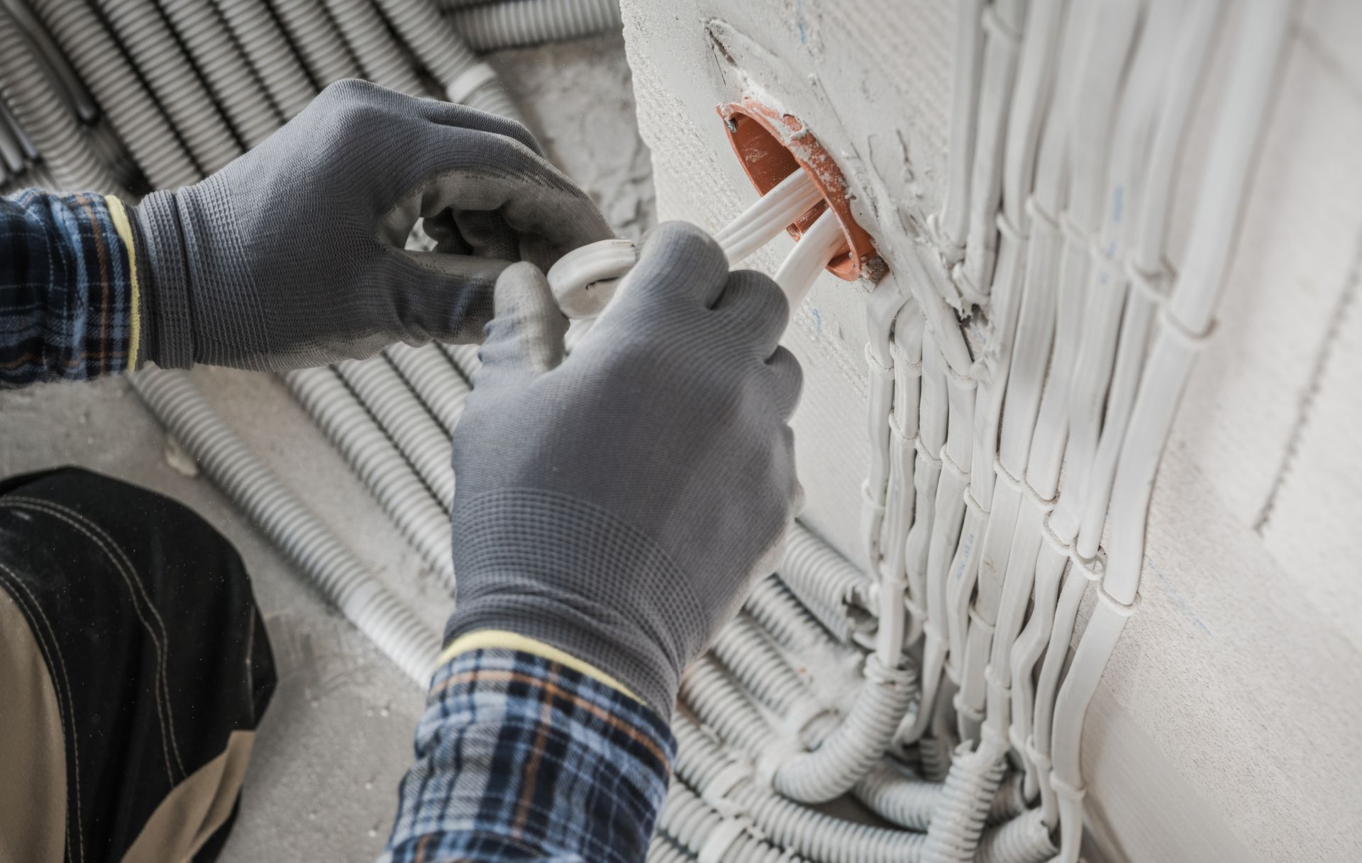 A man is installing electrical wires in a wall.