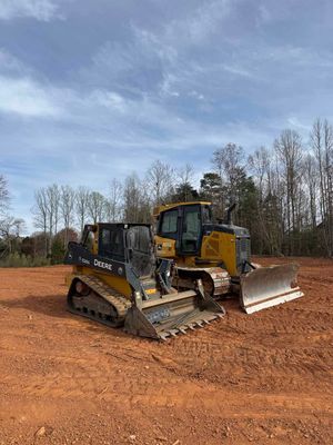 Two bulldozers are parked in a dirt field.