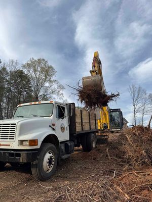A white truck is sitting in a pile of wood chips next to a yellow excavator.