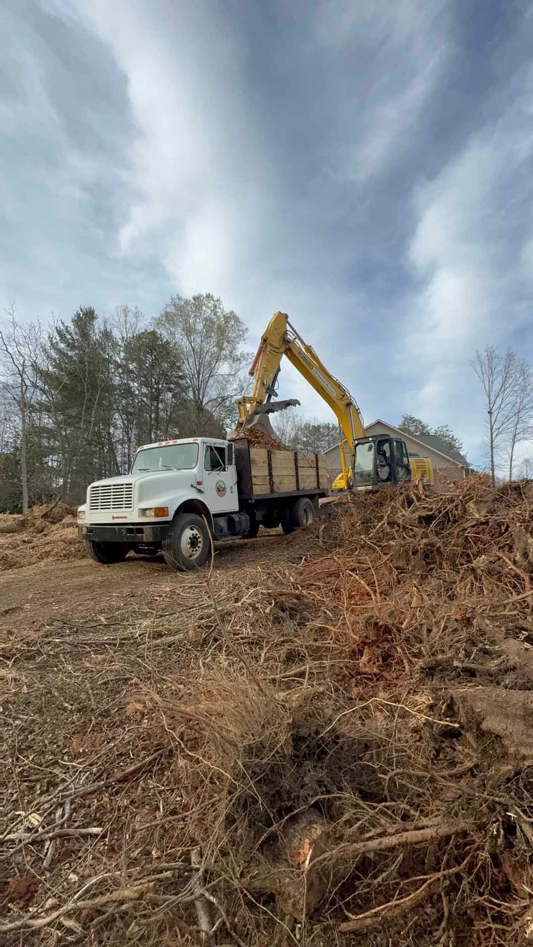 A white truck is driving down a dirt road next to an excavator.