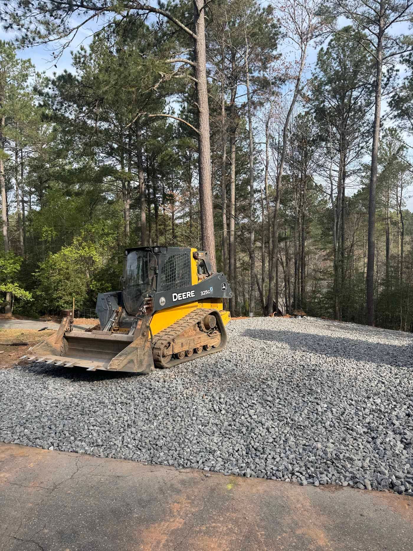A bulldozer is parked on a gravel road in the woods.