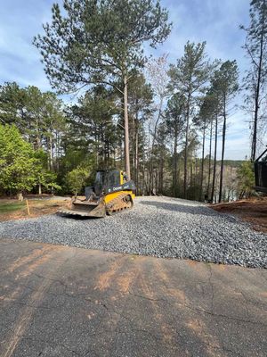 A bulldozer is driving down a gravel road next to a forest.