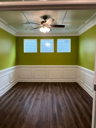 An empty room with green walls and a ceiling fan.