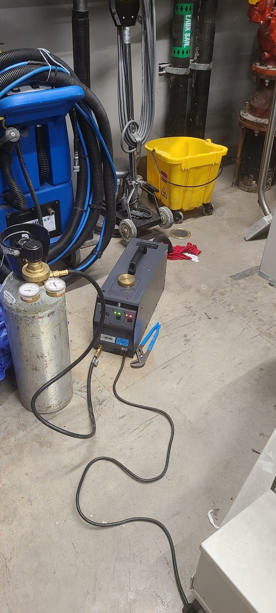 Une machine est posée sur le sol dans une pièce à côté d'une poubelle jaune.