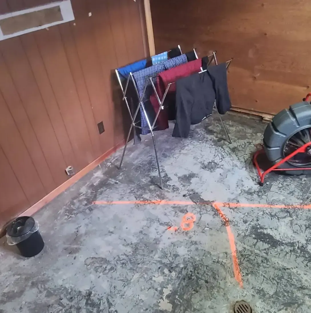 Des vêtements sont suspendus sur un support dans une pièce à côté d'un drain