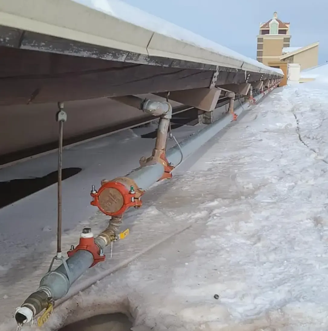 Une rangée de tuyaux suspendus à un toit dans la neige