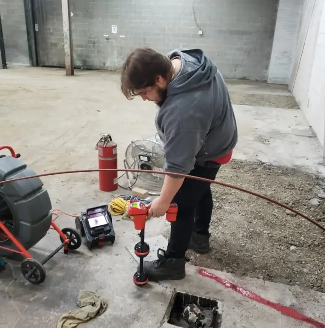 Un homme travaille sur un drain avec un tuyau