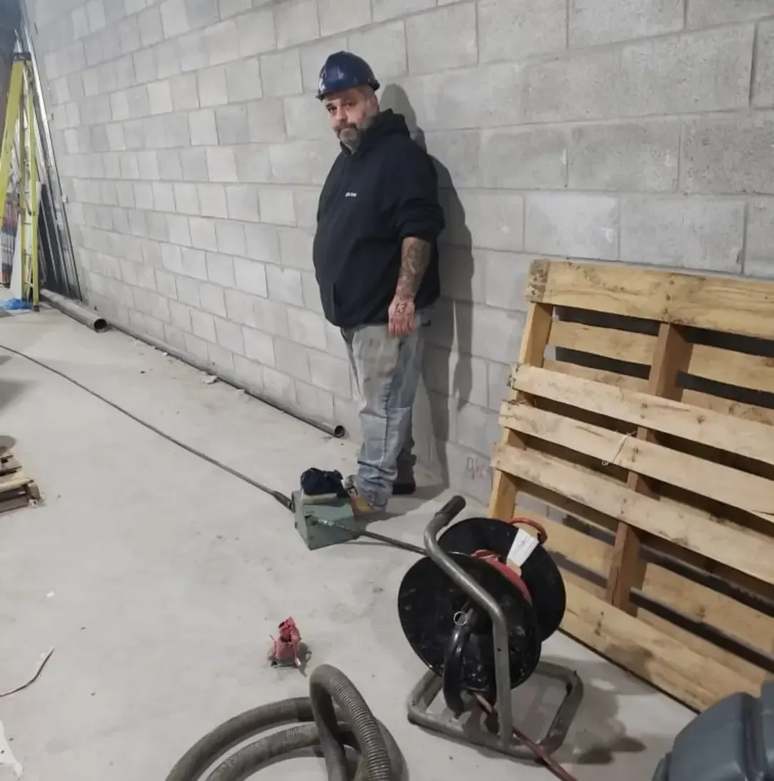 Un homme appuyé contre un mur de briques à côté d'une palette en bois