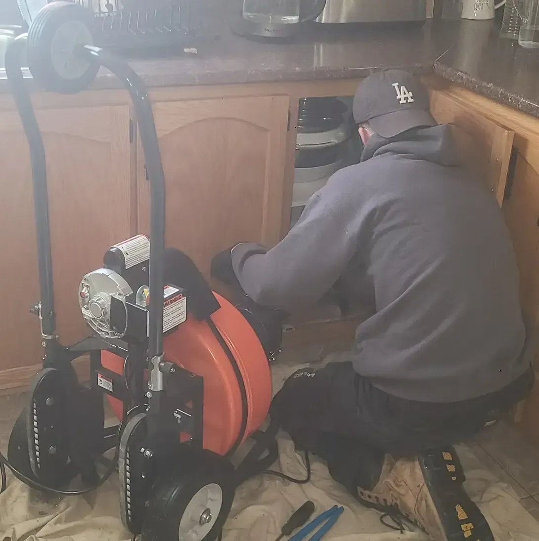Un homme est agenouillé devant une machine dans une cuisine.