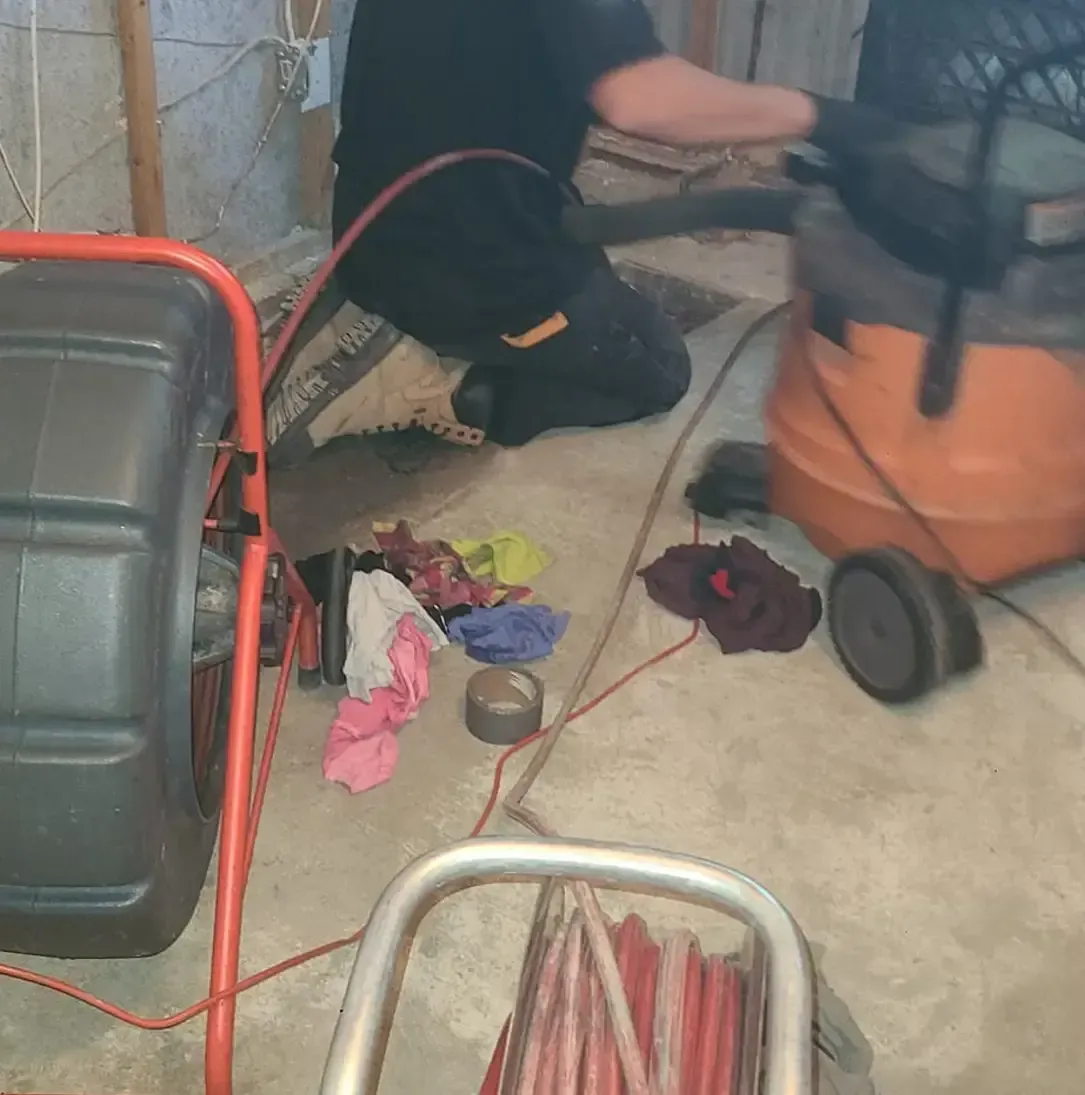 Un homme travaille sur un drain avec un aspirateur