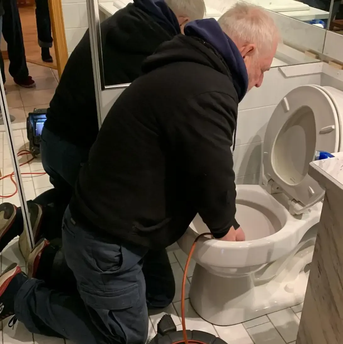 Un homme est à genoux devant des toilettes