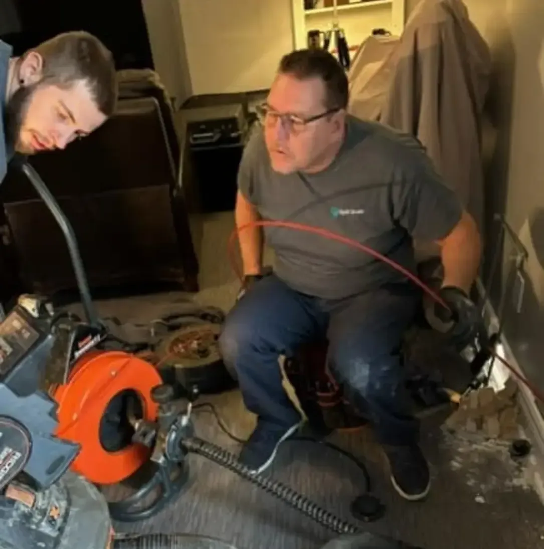 Un homme en chemise grise utilise un déboucheur de canalisations