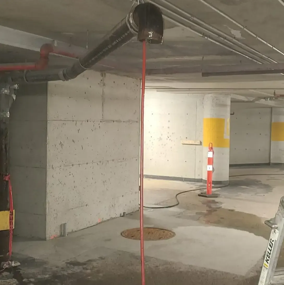 Un tuyau rouge est suspendu au plafond d'un parking.