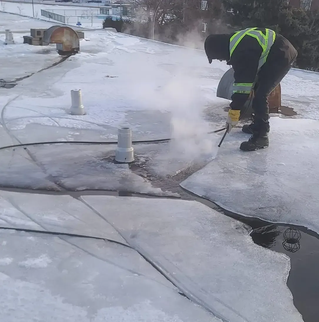 Un homme portant un gilet de sécurité travaille sur un toit enneigé