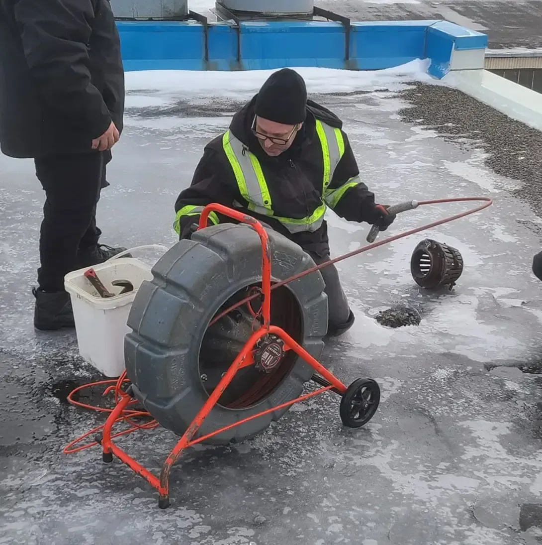 Un homme travaille sur un drain dans la neige