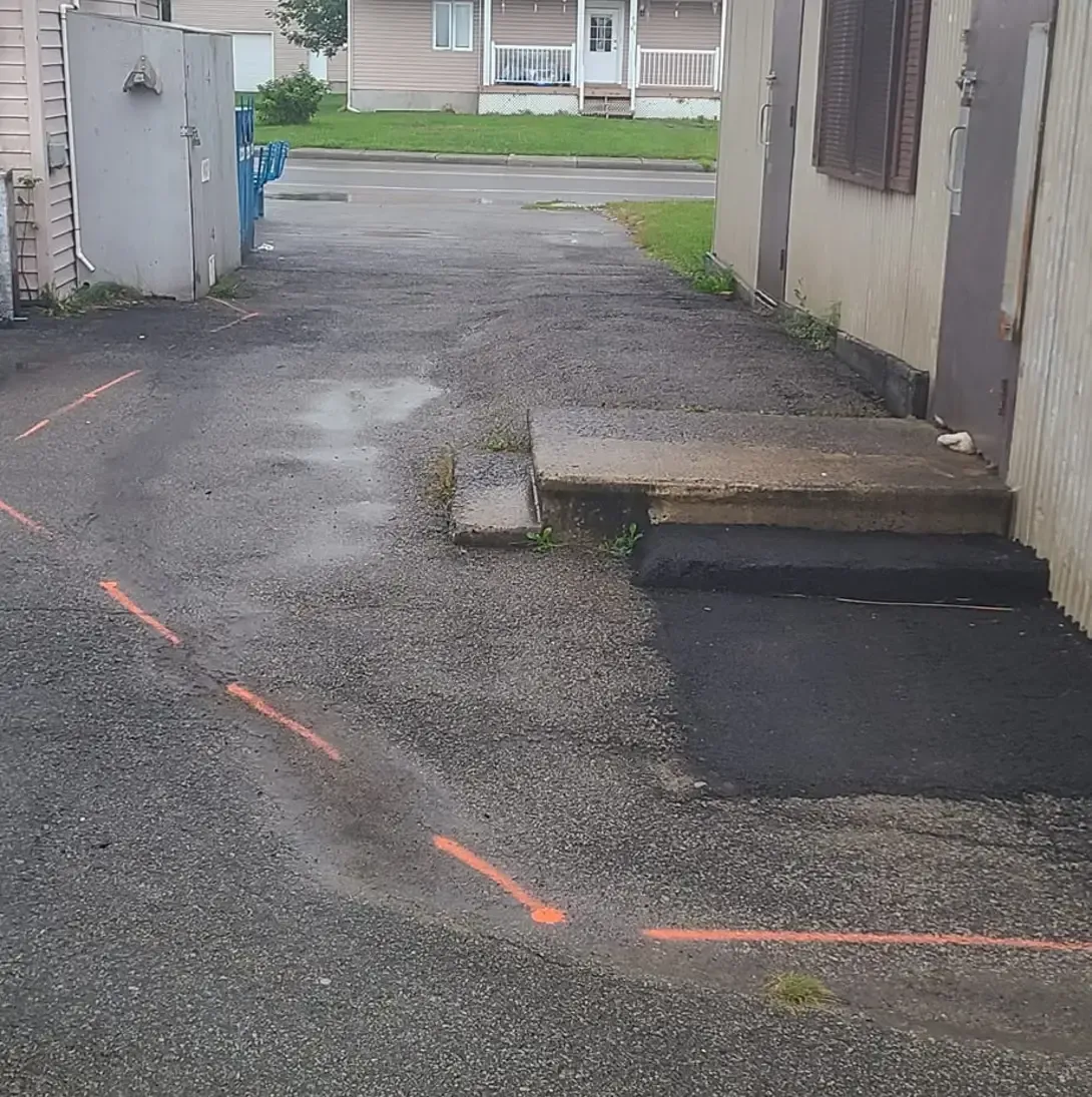 Une allée menant à un bâtiment avec des lignes orange dessus