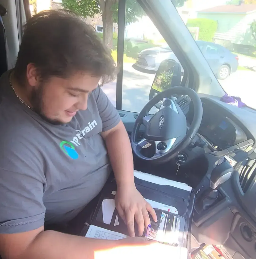 Un homme portant une chemise sur laquelle est écrit ntrain est assis sur le siège conducteur d'une camionnette